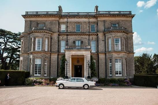 The wedding venue: a stone manor house with a vintage car at the entrance